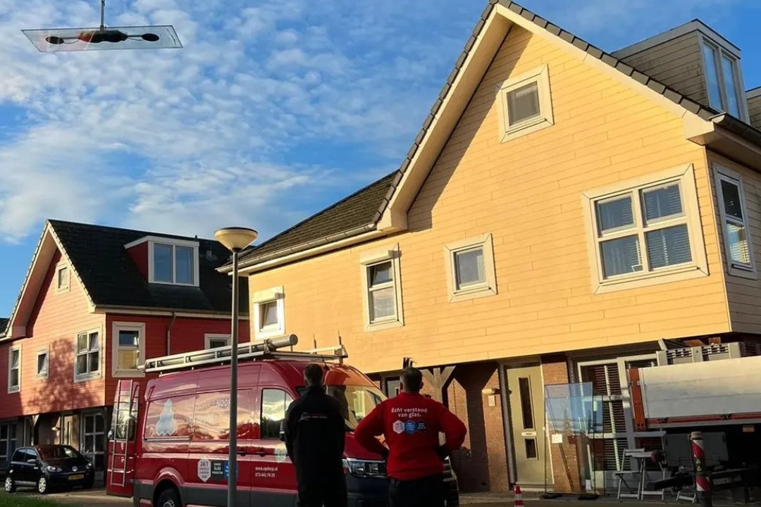 Kraanwagen en bedrijfsbus bij een woning tijdens glasvervanging