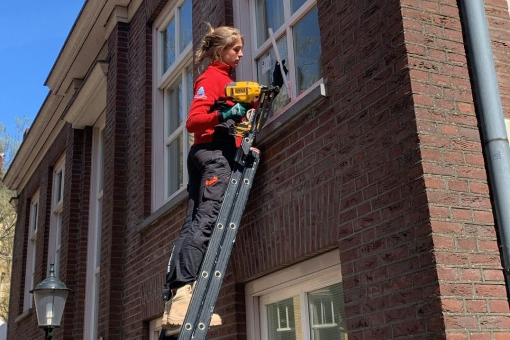 Glaszetter van Glasservice Noord werkt op een ladder aan een raam van een woning