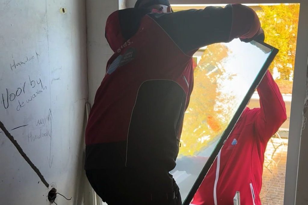 Monteur neemt een oude ruit uit de sponning van een gevel